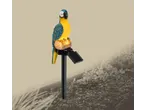 Solar-powered garden stake light in the shape of a blue and yellow parrot on a log.