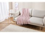Uma sala de estar clara com um sofá bege, uma manta rosa e uma pequena mesa lateral.