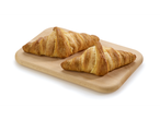 Deux croissants au beurre dorés sur une planche à découper en bois clair.