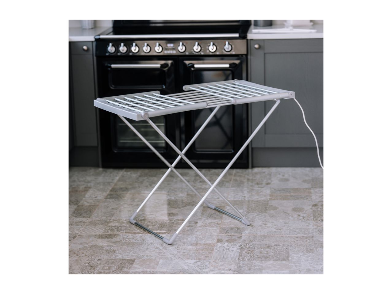 Heated clothes airer in a kitchen with a black oven and grey cabinets.