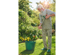 Um homem usando um removedor de ervas daninhas e um balde no jardim.