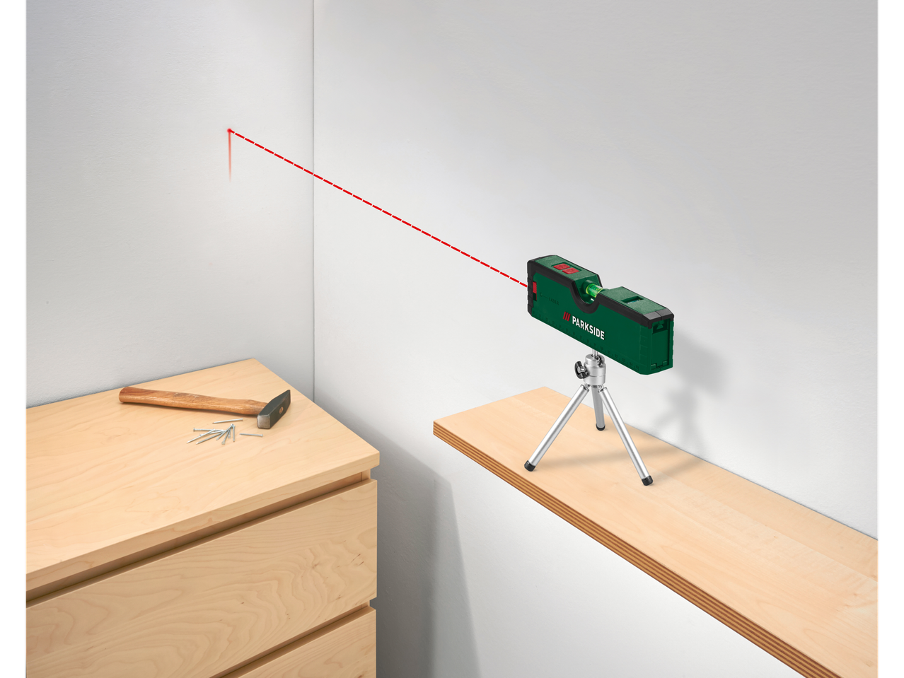 Um nível a laser Parkside verde em um tripé, com um feixe de laser vermelho na parede.