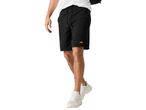 A man wearing black shorts with an orange logo and white sneakers.