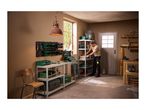 Man organizing tools and storage bins on metal shelving in a workshop.