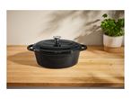 Black cast iron Dutch oven on a wooden countertop with a potted plant.