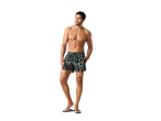 Un bărbat musculos purtând șorturi de baie cu imprimeu tropical de frunze.