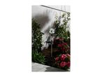 Solar garden stake light with a glass globe, surrounded by red flowers and green plants.
