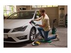 Man polishing a white car with an electric polisher in a garage.