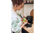 A woman adds vegetables to a Silvercrest air fryer.
