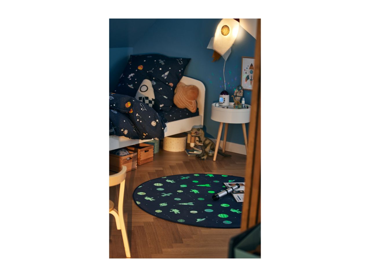 A child's bedroom with space-themed bedding, a rocket lamp, and a glow-in-the-dark rug.