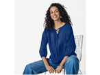 Mulher com blusa azul ESMARA Bægerranke e jeans, sentada numa cadeira.