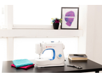 Máquina de costura E-ELEMENT BY PFAFF com tecidos e acessórios numa mesa.