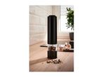 Black electric pepper grinder with mixed peppercorns on a wooden kitchen counter.