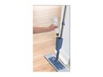 A person refilling the water tank of a spray mop on a wooden floor.