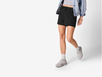 Femeie purtând pantaloni scurți negri și adidași gri.
