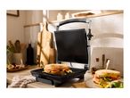 Toasted sandwich maker with a grilled cheese sandwich in a kitchen setting.