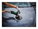 Person polishing a dark car hood with a green and grey electric car polisher.
