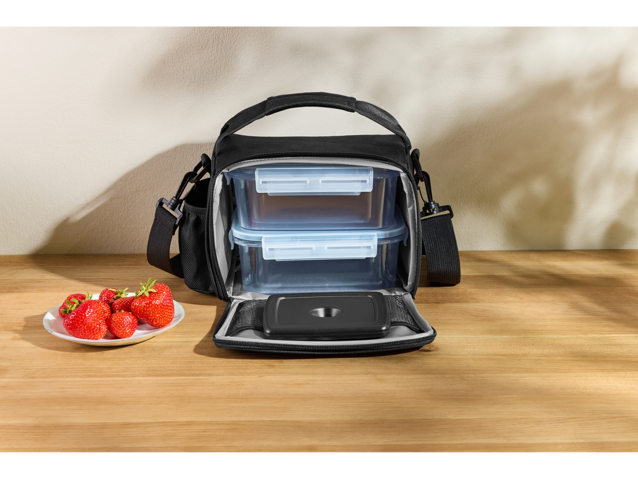 Silvercrest® torba za ručak sa posudama za hranu i tanjirom jagoda na drvenom stolu.