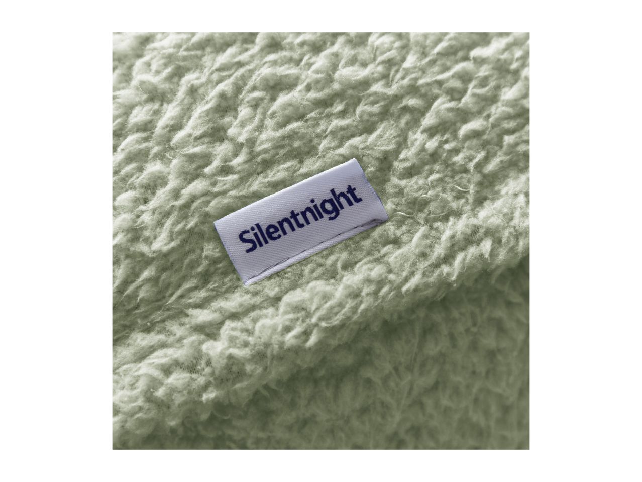 Close-up of a soft, light green fleece blanket with a white label featuring dark blue text.
