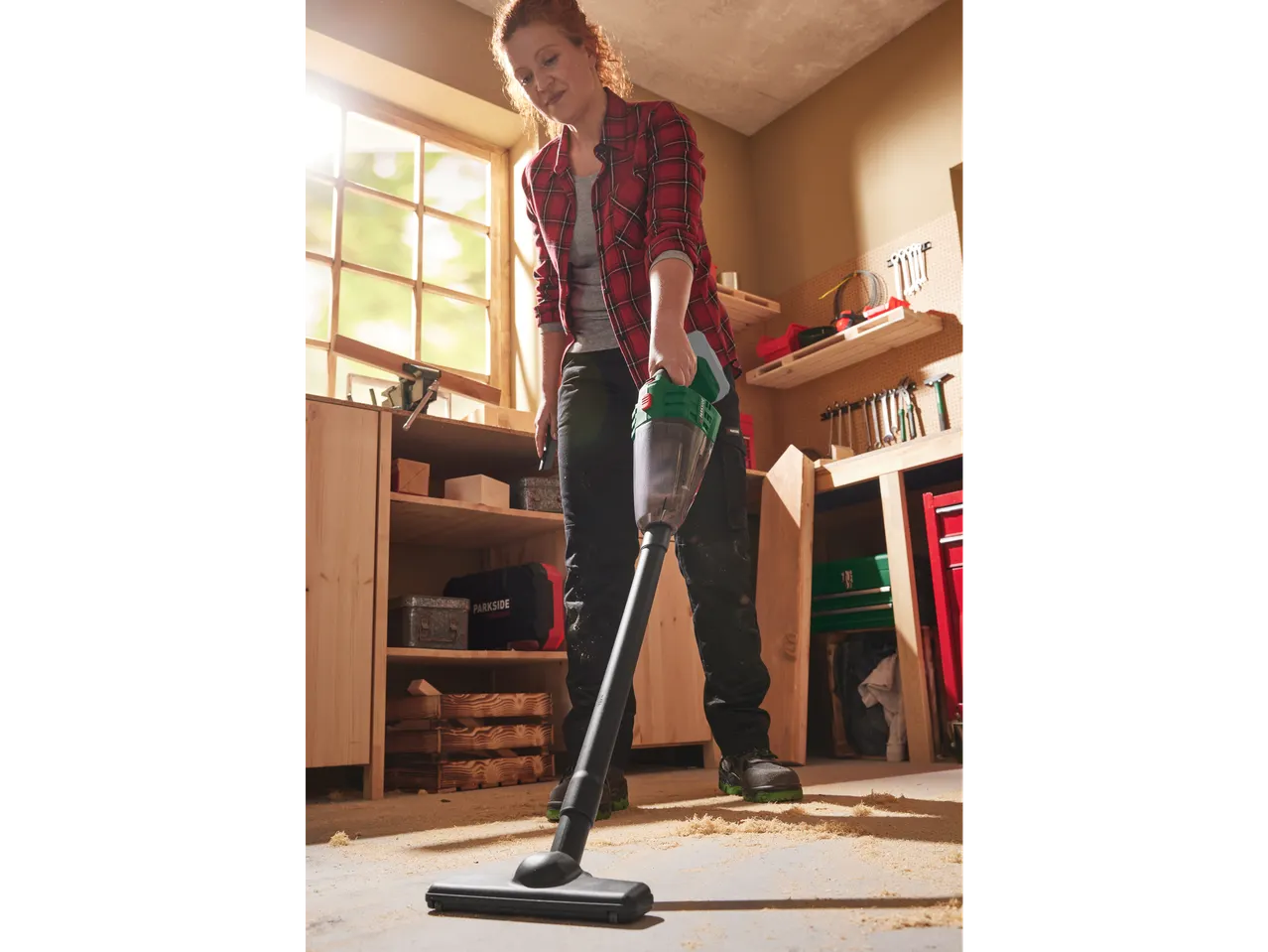 Woman using a PARKSIDE® 20V Cordless Handheld Vacuum Cleaner in a workshop.