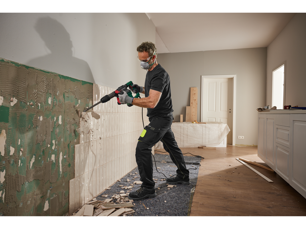 Um homem usa um martelo demolidor Parkside para remover azulejos de uma parede.