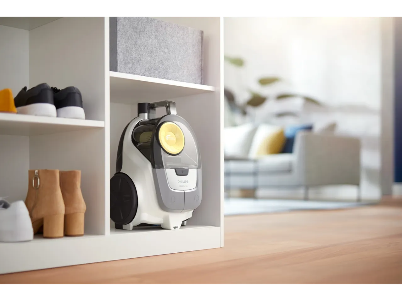Aspirator Philips PowerCyclone într-un dulap alb, cu pantofi și cizme.
