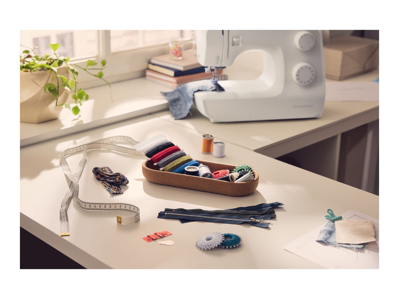 A sewing machine and various sewing accessories arranged on a white table.