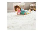 Toddler lying on a white rug, drinking from a pink sippy cup.