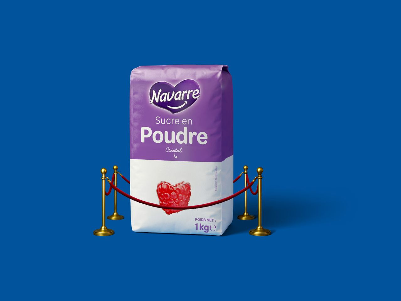 Un sac de sucre en poudre Navarre avec une framboise en forme de cœur, derrière des cordons rouges.