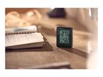 Digital thermometer and hygrometer displaying 27.9°C and 56% humidity on a wooden desk.