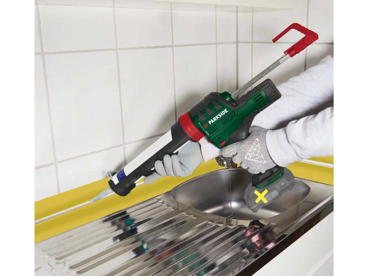 Акумулаторен пистолет за уплътняване Parkside® в употреба за запечатване на кухненска мивка.