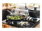 A gas stovetop with a frying pan of broccoli and a pot on separate burners.