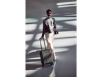Woman traveling with a carry-on suitcase and handbag.