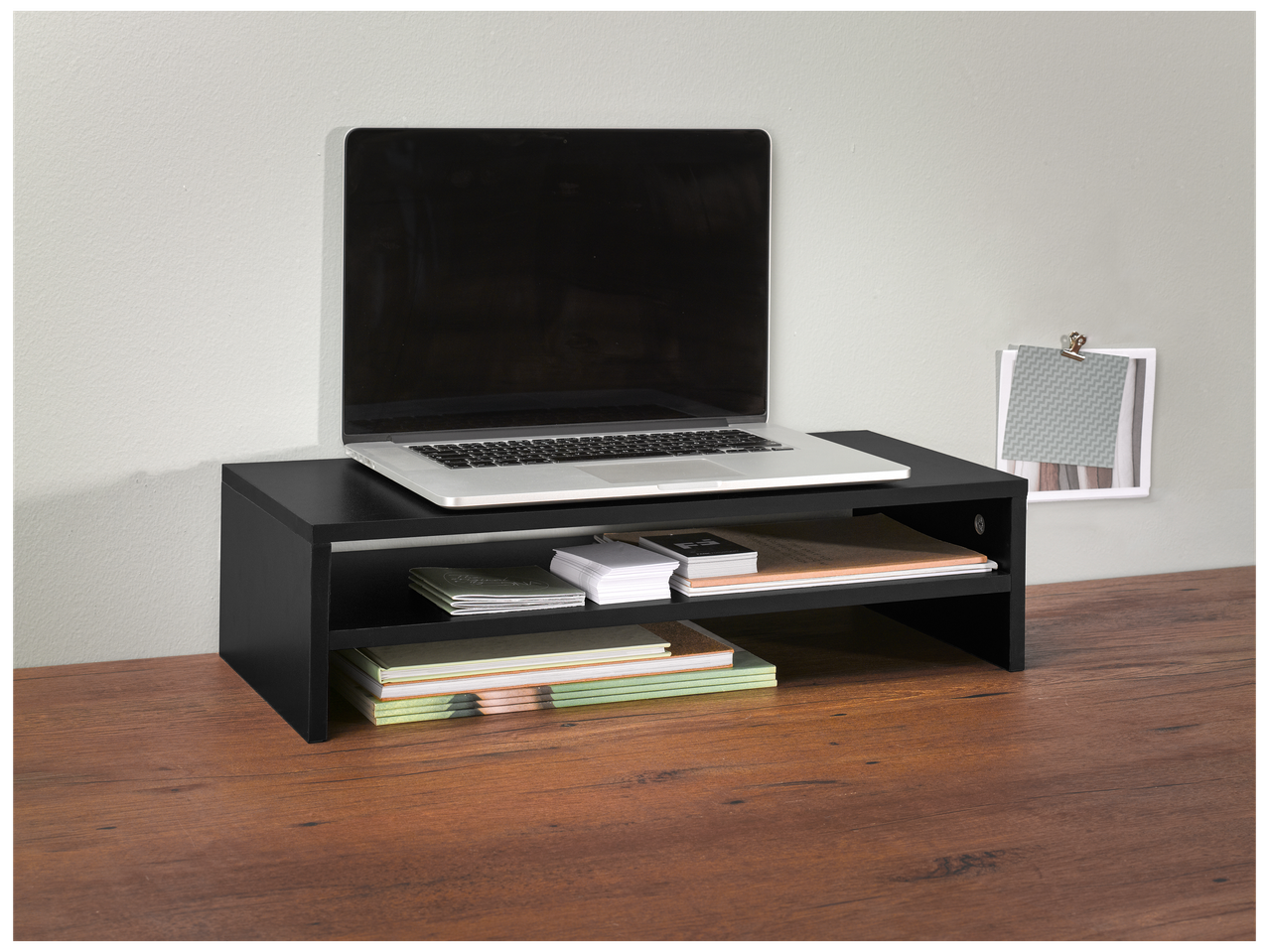 Support d'écran noir avec un ordinateur portable, des carnets et des cartes sur un bureau en bois.