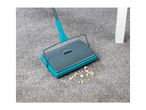 A Belray carpet sweeper cleans up crumbs on a grey carpet.