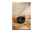 Black silicone air fryer basket on a wooden table with a small bowl of spices.