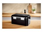 Black metal bread bin with hinges on a wooden kitchen countertop.