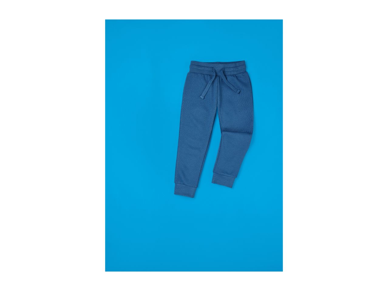 Blue sweatpants with a drawstring waist on a blue background.