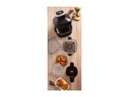 Air fryer with chicken wings and potato wedges, glass containers, and spices on a wooden table.