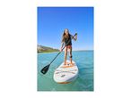 Young woman paddleboarding on clear water, wearing a life vest and swimsuit.