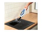 Handheld steam cleaner cleaning a black induction hob on a wooden countertop.