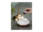 Adding essential oil to a gold-colored aroma diffuser filled with water.