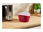 A red silicone popcorn maker with a clear lid next to a SilverCrest microwave.