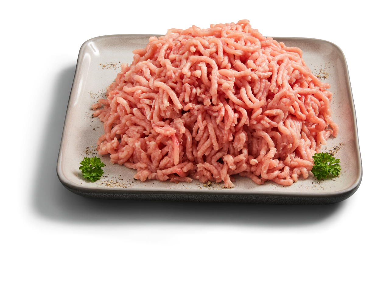 Ein Haufen rohes Hackfleisch auf einem quadratischen Teller, garniert mit Petersilie und Pfeffer.
