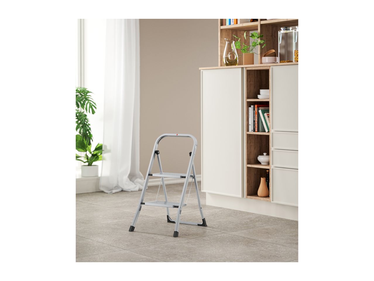 A silver step stool stands on a tiled floor in a room with a cabinet and a plant.