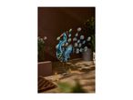 Decorative metal peacock with solar lights on a wooden patio with plants.