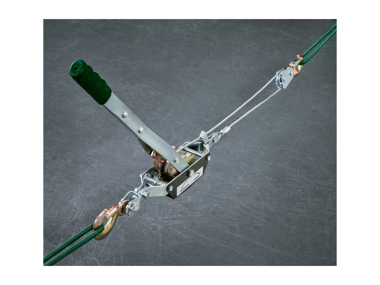 A green-handled cable puller with a steel cable and hooks on a dark background.