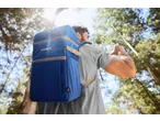 Man wearing a blue CRIVIT Cooler Bag Backpack, drinking water in a forest.