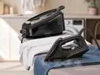 A SilverCrest steam generator iron and iron on an ironing board with clothes.