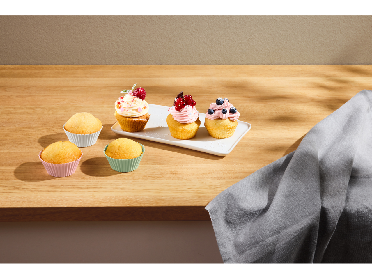 Silvercrest® silikonski kalupi sa mafinima i ukrašenim kolačićima na drvenoj radnoj ploči.
